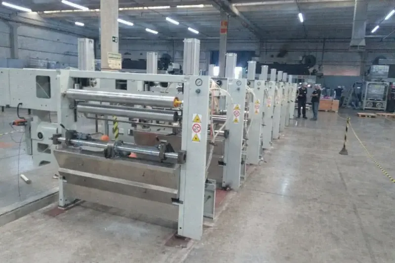 Técnicos ajustando estruturas durante instalação de máquina rotográfica